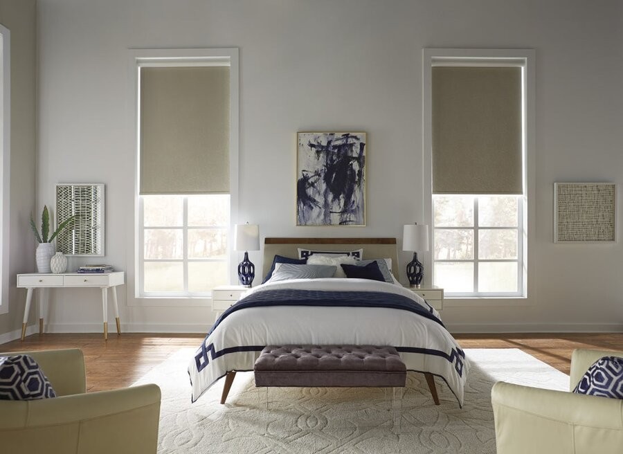 A bedroom featuring a window on either side of the bed with motorized shades lowered halfway on each.