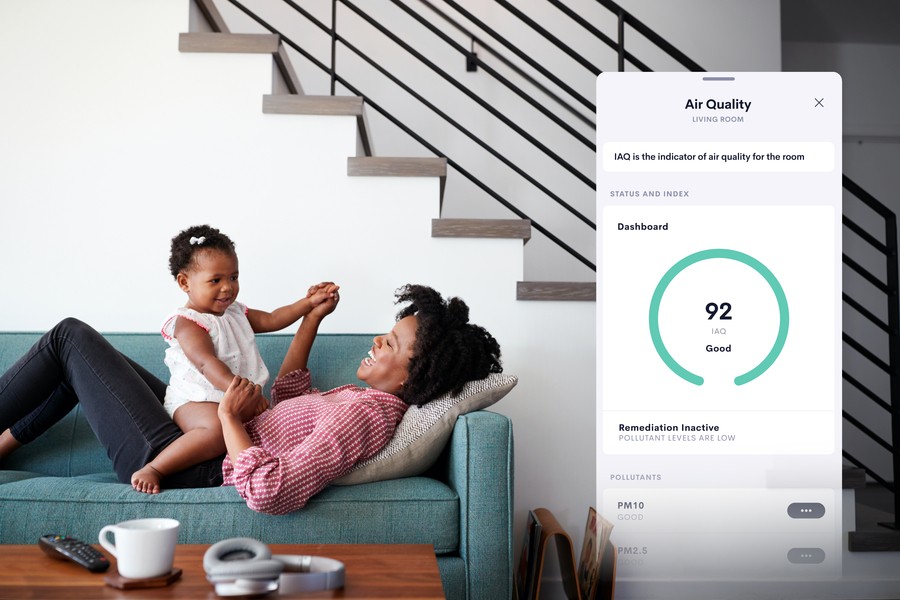 Family sitting on a couch with a picture of a Crestron Home app on the climate feature superimposed on top. 